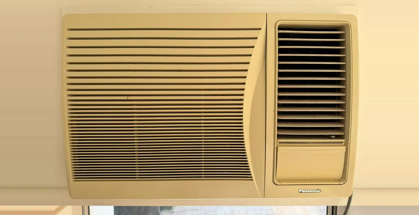An old beige Panasonic window air conditioner, the kind replaced with a wall split system